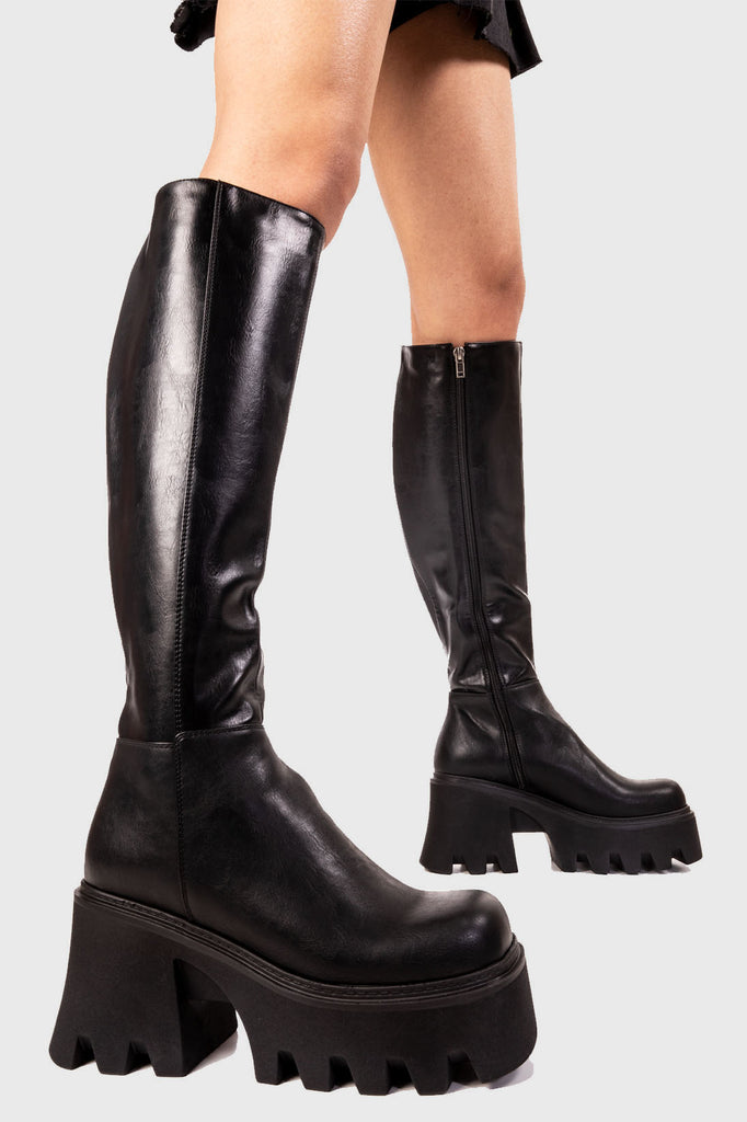 STRAFING Sideways Chunky Platform Knee High Boots in Black faux leather. These black vegan Platform Boots feature on our chunky platform sole, simple steps with exceptional comfort. Features a stretchy gusset in on the back of the upper alongside a functional zip. Made with eco-friendly materials and 100% cruelty-free, these platform boots are as ethical as they are comfortable! - Platform Height: - Black Zipper - Stretchy Gusset - Chunky Platform Sole - Round Toe - 100% Vegan SKU: LMF 2252 - BlackPU