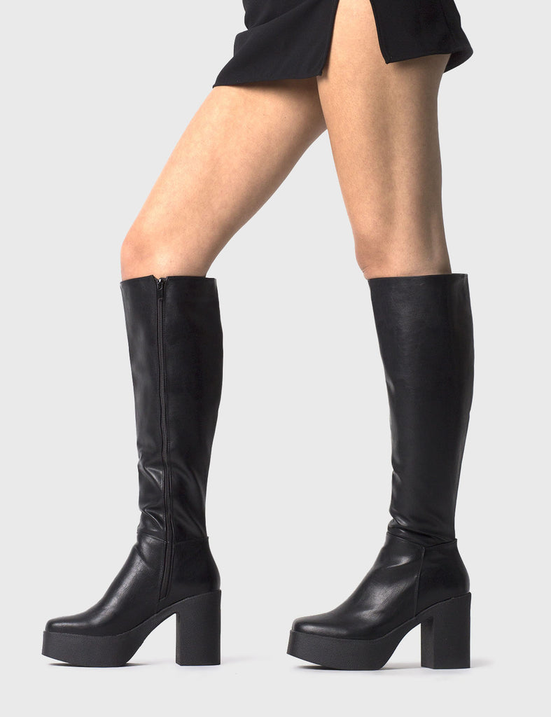 THE TRENDING ONE Slick Nicks Platform Knee High Boots in Black faux leather. These Black vegan Boots feature an elegant minimalist design and a Platform sole and heel, perfect for adding height and style to any outfit. Made with eco-friendly materials and 100% cruelty-free, these boots are as ethical as they are stylish. - Platform Height: 1.25 inch - Heel Height: 4 inch - Knee High length - Black zipper - Platform sole - Square toe - 100% vegan SKU: LMF 0856 - BlackPU