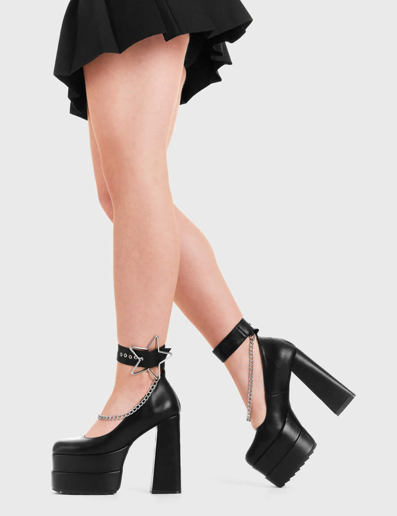 SHOOTING STARS Catching Stars Platform Heels in Black faux leather. These platform boots feature a silver star buckle with Silver hanging chains, keeping it nice and classy. Made with eco-friendly materials and 100% cruelty-free, these platform boots are as ethical as they are chic. - Platform Height - Silver Star buckles - Adjustable straps - Silver chains - Shark teeth grip - High Heel - 100% vegan SKU: LMF 3316 - BlackPU