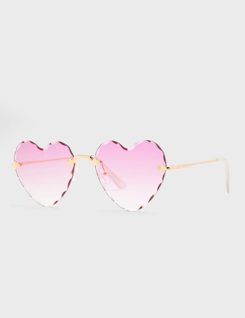 Eye Candy Heart Sunglasses. These Heart sunglasses feature antique style Gold arms, and a Pink tinted heart shaped lens.