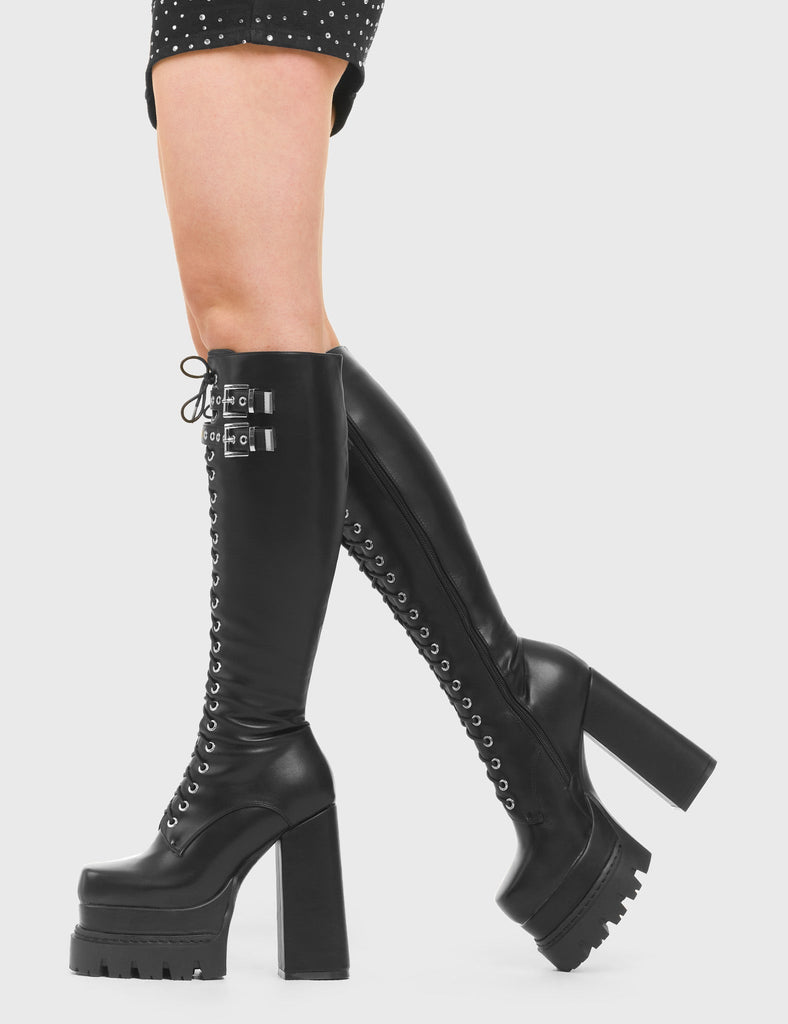 PLAYA Game Changer Chunky Platform Knee High Boots in Black faux leather. These vegan Boots feature a lace up design and Black stitch detailing with two adjustable straps, accompanied by silver buckled and eyelets. Made with eco-friendly materials and 100% cruelty-free, these boots are as ethical as they are trendy! - Heel Height - Knee high length - Lace up design - Two adjustable straps - Silver buckles and eyelets - Black stitching - Black zip - Rubber grip sole - SKU: LMF 3987 - BlackPU