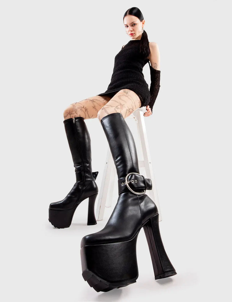 Not Your Basic Boots! Kick Start Platform Knee High Boots in Black faux leather. These platform boots feature a minimalist design, with a large Silver buckle around the ankle on our platform sole and curved heel. Made with eco-friendly materials and 100% cruelty-free, these platform boots are as ethical as they are Trendy. - Platform Height - Heel Height - Black zip - Large Silver buckle and eyelets - Curved Heel - Platform Sole - 100% vegan SKU: LMF 2996 - BlackPU