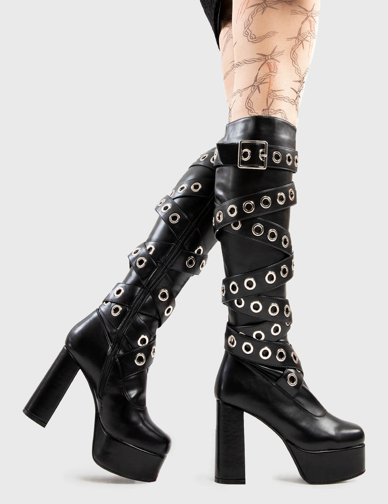 Sizzling Stompers Manhunt Platform Knee High Boots in Black faux . These platform boots feature a large eyelet design that twists up the boot, set new fashion trends with these iconic boots.Made with eco-friendly materials and 100% cruelty-free, these platform boots are as ethical as they are Iconic! - Platform Height - Heel Height - Black Zip - Knee high length - Silver eyelet and square shaped buckles - Platform sole - Round Toe - 100% vegan SKU: LMF 2820 - BlackPU