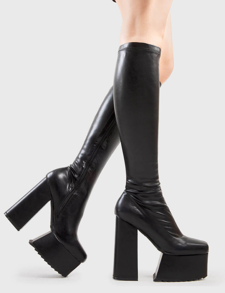 Not Your Basic Boots Return The Favour Platform Knee High Boots in Black faux leather. These platform boots feature a minimalist design, with a stretchy fitted feel, the perfect pair with any outfit. Made with eco-friendly materials and 100% cruelty-free, these platform boots are as ethical as they are Cool! - Platform Height - Heel Height - Black Zipper - Fitted feel - Knee length - Platform sole - Shark's teeth grip - High Heel - 100% vegan SKU: LMF 2875 - BlackPU