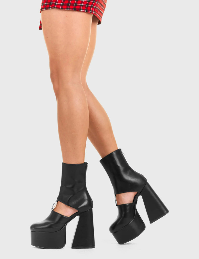 RING ME Ring Me Platform Ankle Boots Ankle Boots in Black faux leather. These platform boots feature a minimalist look with a cut out design, keeping it nice and classy. Made with eco-friendly materials and 100% cruelty-free, these platform boots are as ethical as they are chic. - Platform Height - Claf length - Cut out design - Silver circle buckle - Flared heel - High Heel - 100% vegan SKU: LMF 3354 - BlackPU