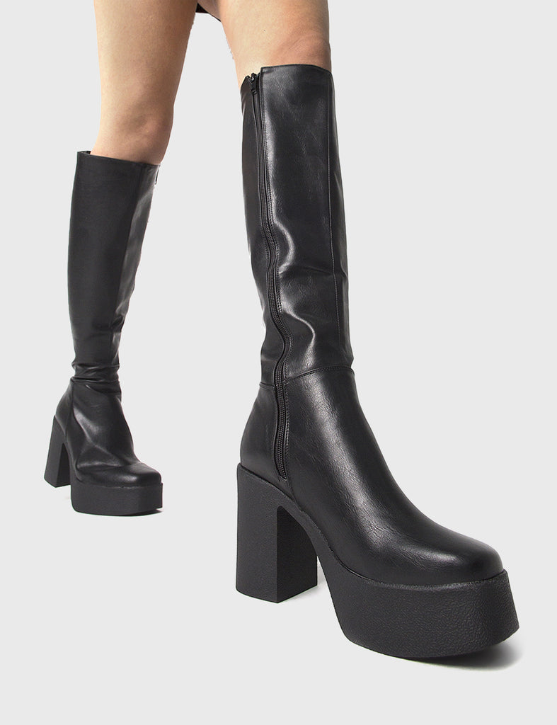 THE TRENDING ONE Slick Nicks Platform Knee High Boots in Black faux leather. These Black vegan Boots feature an elegant minimalist design and a Platform sole and heel, perfect for adding height and style to any outfit. Made with eco-friendly materials and 100% cruelty-free, these boots are as ethical as they are stylish. - Platform Height: 1.25 inch - Heel Height: 4 inch - Knee High length - Black zipper - Platform sole - Square toe - 100% vegan SKU: LMF 0856 - BlackPU