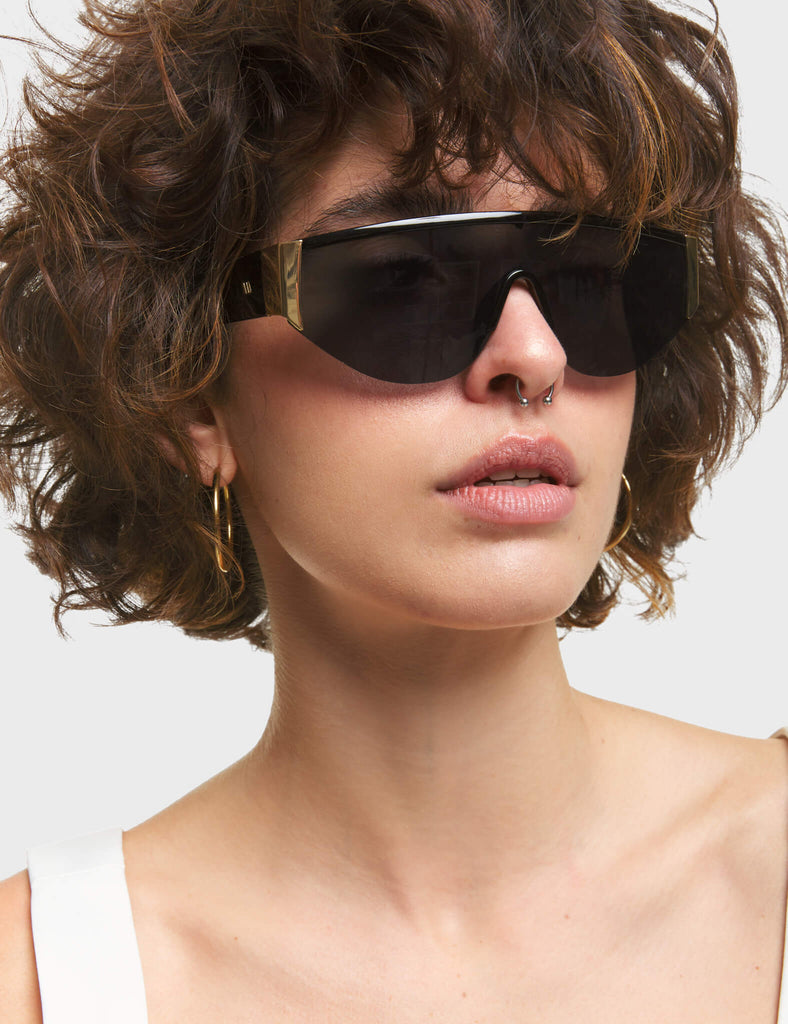 Throw Shade Visor Sunglasses. These Visor sunglasses feature Gold touches on the frame, and a Black tinted lens.