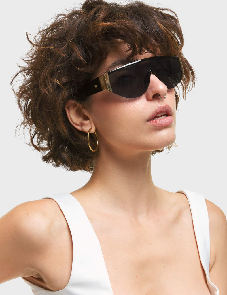 Throw Shade Visor Sunglasses. These Visor sunglasses feature Gold touches on the frame, and a Black tinted lens.
