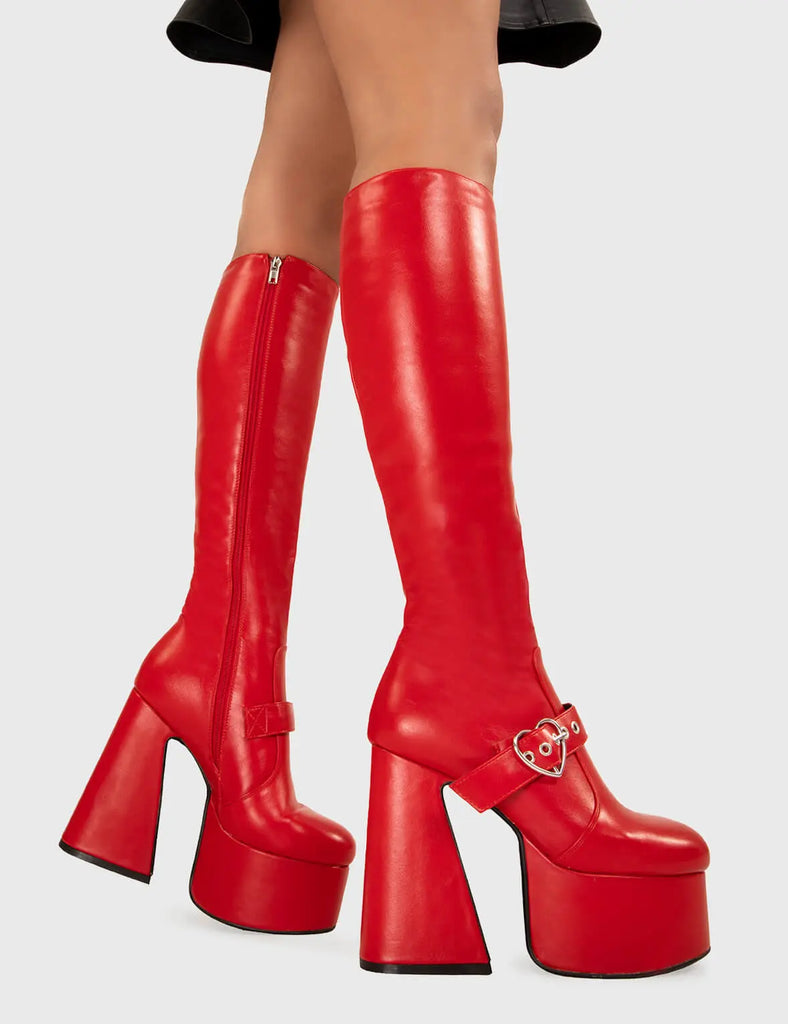 YOU STOLE MY HEART Walk With Love Platform Knee High Boots in Red faux leather. These platform boots feature a minimalist look with a Flared heel, and an adjustable strap. Made with eco-friendly materials and 100% cruelty-free, these platform boots are as ethical as they are chic. - Platform Height - Knee high - Silver heart buckle - Flared heel - High Heel - 100% vegan SKU: LMF 3358 - RedPU