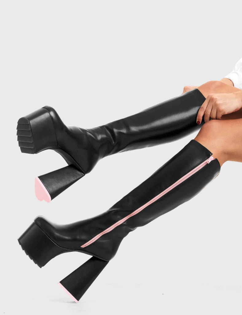 PEACE AND LOVE Wild Child Platform Knee High Boots in Black Faux Leather. These vegan western Boots feature heart shaped heel, with a red sole and shark teeth grips, very classy. Made with eco-friendly materials and 100% cruelty-free, these boots are as ethical as they are edgy! - Chunky Platform heels - Knee length - Shark teeth grip - Heart shaped heel - Pink heel sole - Rounded toe - 100% vegan SKU: LMF 3634 - BlackPU/Pink