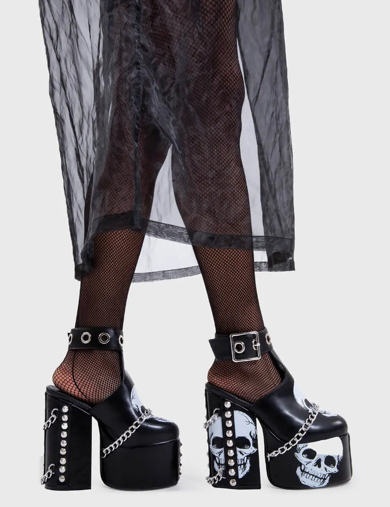 Skull Stomperss
 
 Hidden Closet Platform Heels in Black faux leather. These platform heels feature a skull design throughout and T bar structure ankle strap with square shaped buckle, make bold steps and leave a lasting impression.
 
 - Platform Height
 - Heel Height
 - Adjustable ankle strap
 - Silver eyelets and square shaped buckles
 - Skull design
 - Silver chain
 - Silver spiked studs
 - Chunky Platform sole
 - Round Toe 
 - 100% vegan