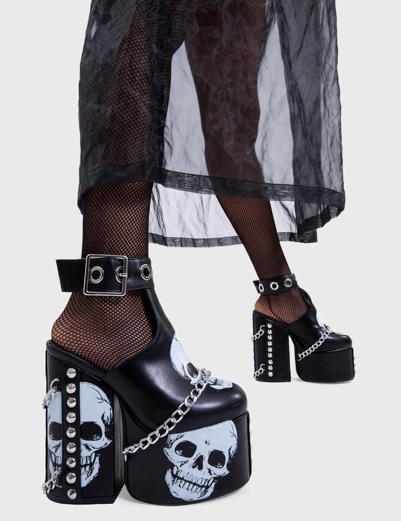 Skull Stomperss
 
 Hidden Closet Platform Heels in Black faux leather. These platform heels feature a skull design throughout and T bar structure ankle strap with square shaped buckle, make bold steps and leave a lasting impression.
 
 - Platform Height
 - Heel Height
 - Adjustable ankle strap
 - Silver eyelets and square shaped buckles
 - Skull design
 - Silver chain
 - Silver spiked studs
 - Chunky Platform sole
 - Round Toe 
 - 100% vegan