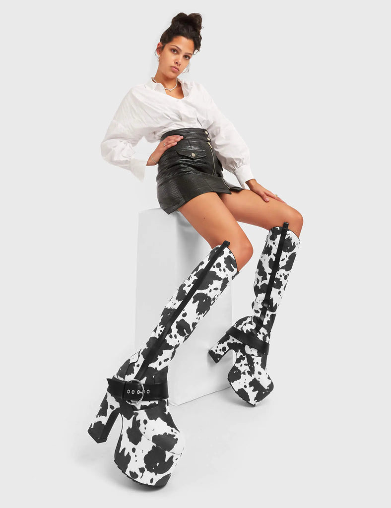 ANIMALISTIC
 
 Rhinestone Cowboy Chunky Platform Knee High Boots in Cow Print faux suede. These vegan Platform Boots feature an ICONIC western cow print on a Chunky Platform sole and heel, also features a adjustable strap across the front. Made with eco-friendly materials and 100% cruelty-free, these boots are as ethical as they are wild!
 
 
 - Platform Height: 
 - Heel Height: 
 - Cowprint Design
 - Knee High Length 
 - Black Zipper
 - Platform Sole
 - Pointed Toe
 - 100% vegan
 
 SKU: LMF 5118 - Cowprint