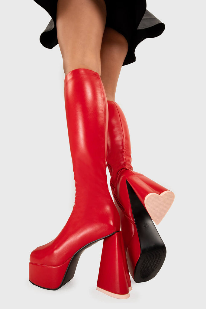 LOVEABLE 
 
 Sweet Talker Platform Knee High Boots in Red faux leather. These platform boots feature a minimalist look with a heart shaped heel, keeping it nice and classy. Made with eco-friendly materials and 100% cruelty-free, these platform boots are as ethical as they are chic.
 
 - Platform Height
 - Knee length
 - Heart shaped heel
 - Pink sole
 - Red zip
 - High Heel
 - 100% vegan 
 
 SKU: LMF 3313 - RedPU