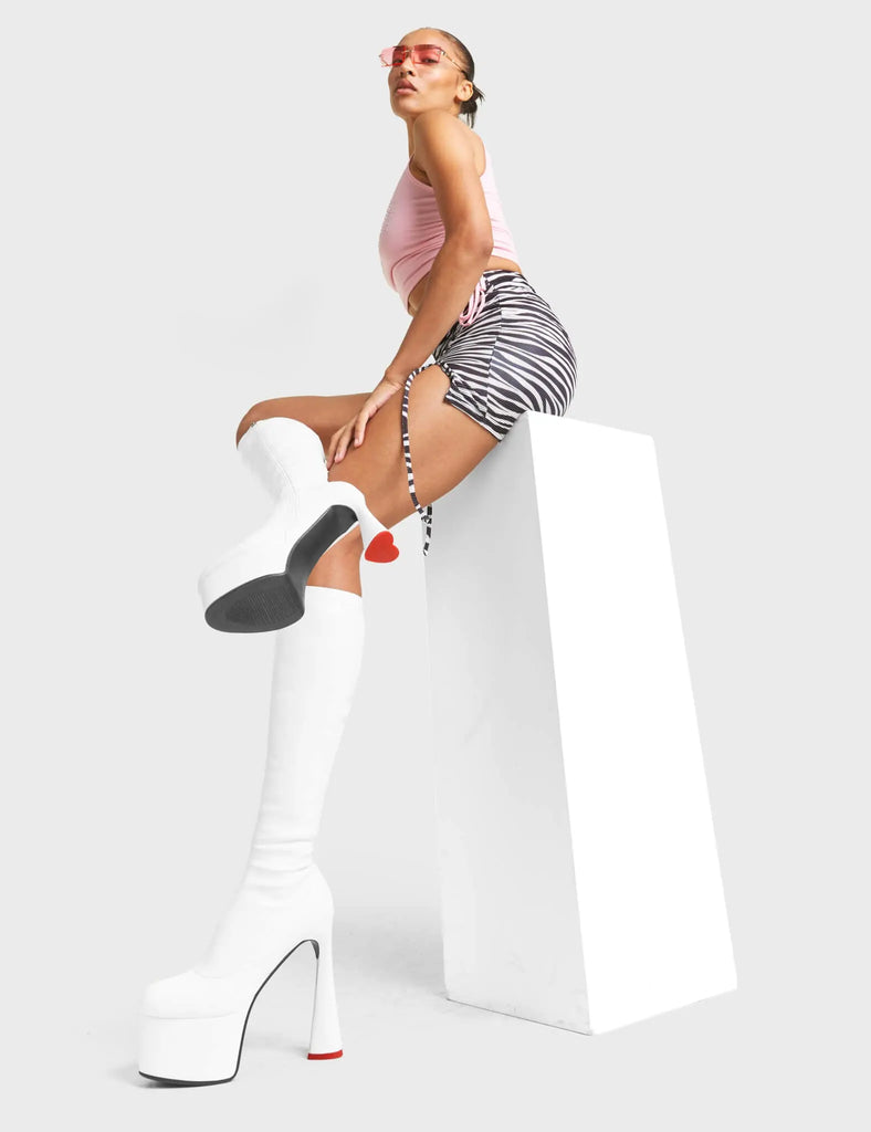 FOREVER TOGETHER
 
 Talk Platform Knee High Boots in White Stretch faux leather. These platform boots feature on our platform sole and highlights our heart shaped heel with a red heart at the bottom. Made with eco-friendly materials and 100% cruelty-free, these platform boots are as ethical as they are Legendary!
 
 - Platform Height
 - Heel Height
 - Black Zip
 - Knee High Length
 - Stretch Upper
 - Platform Sole
 - Heart Heel
 - Heart Detail
 - Round Toe
 - 100% vegan
 
 SKU: LMF 4471 - WhitePU
